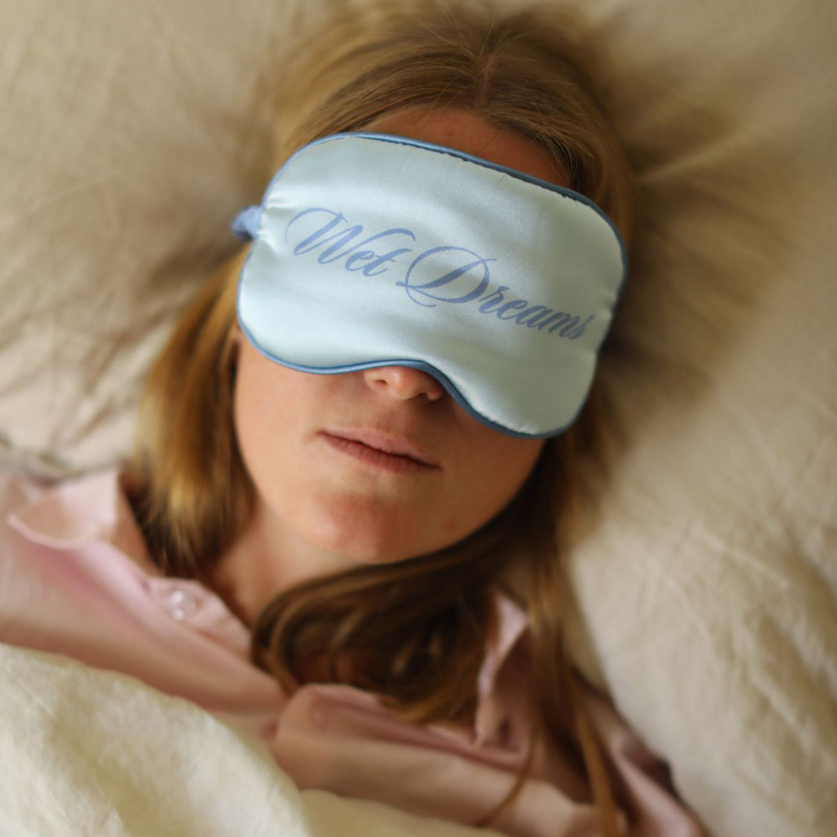 Blå natmaske, kan også bruges som blindfold med teksten Wet Dreams på, på kvinde der ligger i seng