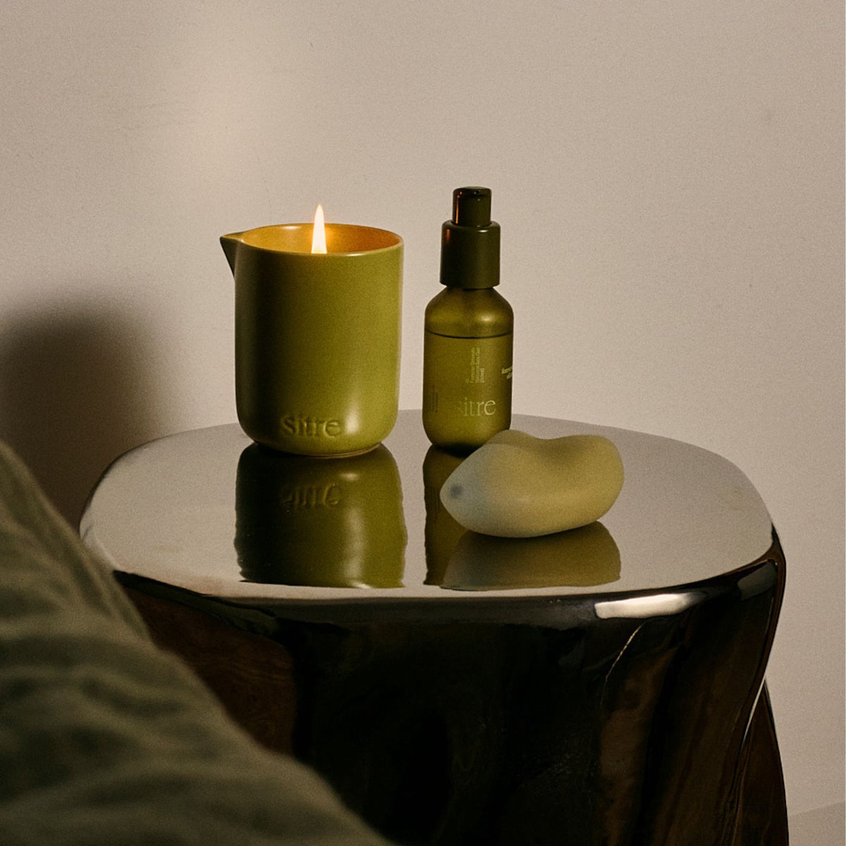 Sitre New Heights vibrator med Sitre massageolie og massage candle på et grønt sidebord