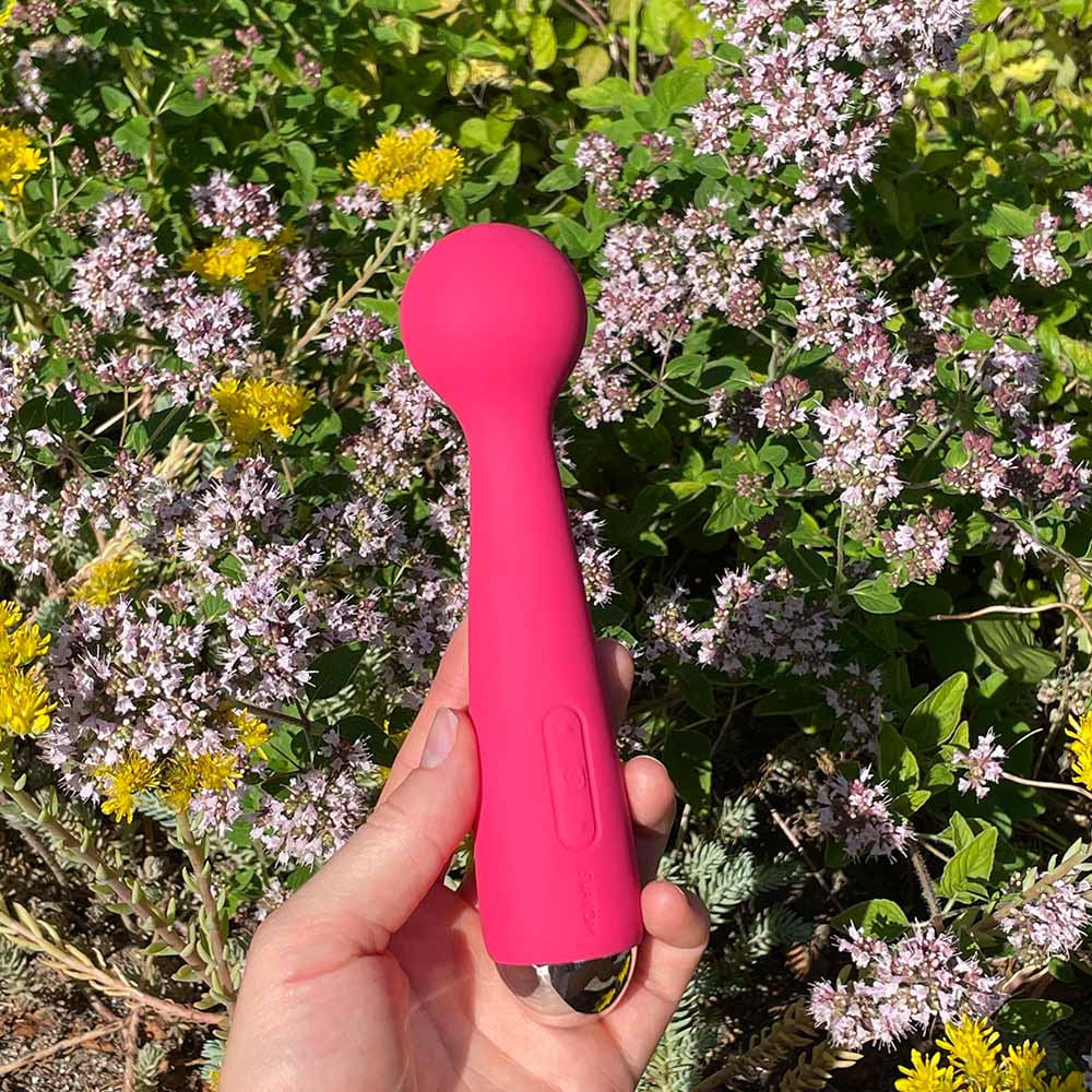 Mini wand vibrator fra svakom med vibrerende hoved hoved violet i rød, blomster baggrund i hånd